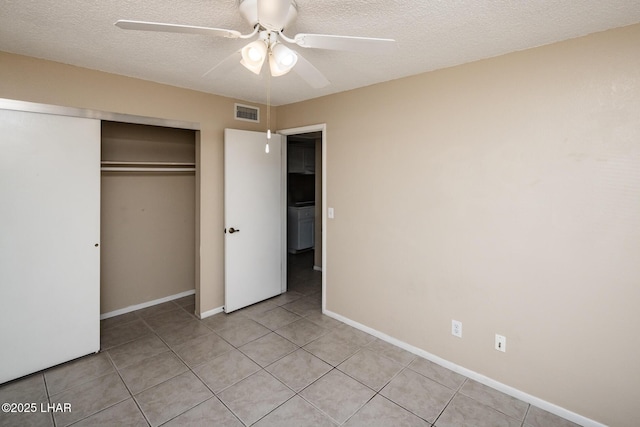 unfurnished bedroom with ceiling fan, a closet, a textured ceiling, and light tile patterned flooring