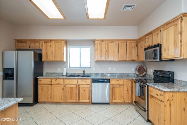 kitchen featuring appliances with stainless steel finishes, light stone countertops, sink, and light tile patterned floors