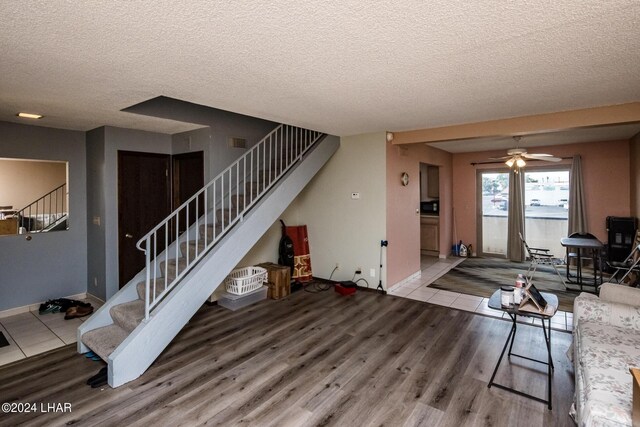 living room with ceiling fan, wood-type flooring, and a textured ceiling