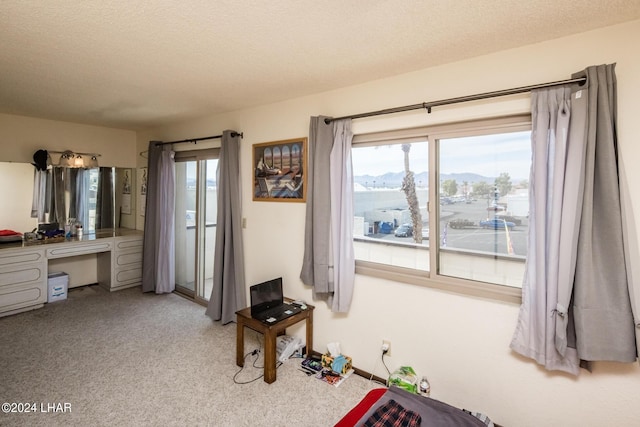 bedroom featuring a mountain view, carpet flooring, built in desk, and a textured ceiling