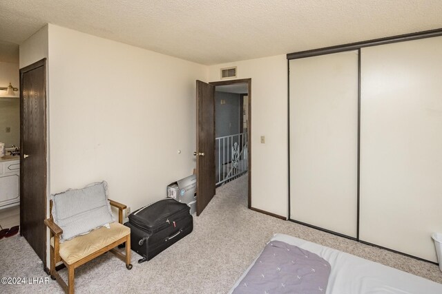 bedroom with a closet, light carpet, and a textured ceiling