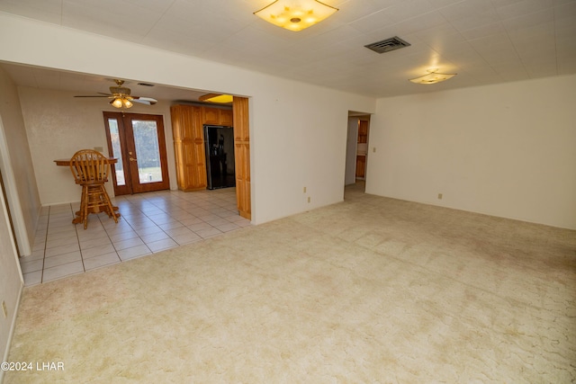 spare room featuring light carpet, ceiling fan, and french doors