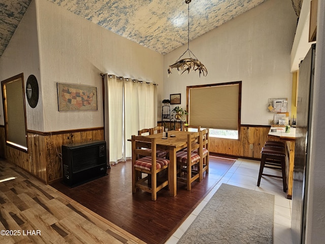 dining space featuring heating unit, wood walls, dark wood-type flooring, and wainscoting