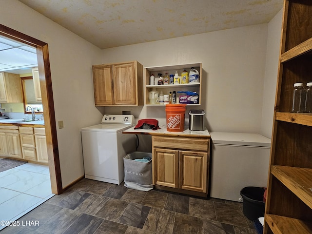 washroom with cabinet space, a sink, washer / dryer, and baseboards