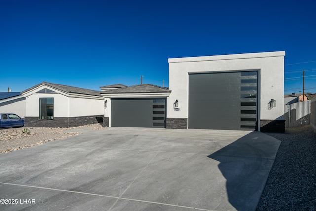 view of front of house with stone siding, an attached garage, and stucco siding