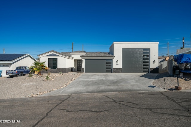 view of front of property featuring a garage, stone siding, driveway, and stucco siding