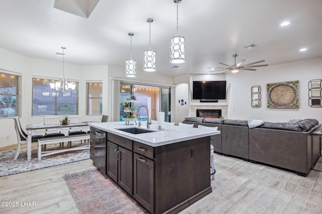 kitchen featuring visible vents, dark brown cabinetry, dishwashing machine, a glass covered fireplace, and a sink