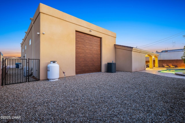 view of home's exterior with stucco siding, an outbuilding, central AC, fence, and a patio area