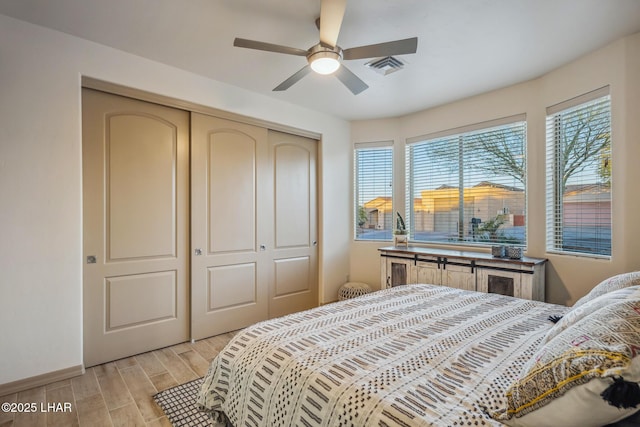 bedroom featuring a ceiling fan, visible vents, a closet, and wood finish floors