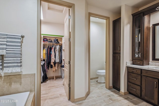 full bathroom featuring vanity, a bathtub, wood tiled floor, and toilet