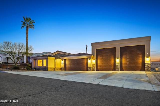 view of front of property with stone siding, stucco siding, concrete driveway, and a garage