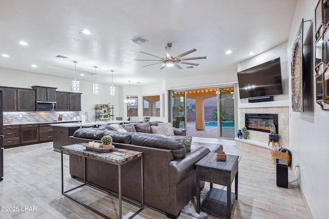 living room with visible vents, recessed lighting, light wood-style floors, and a tile fireplace