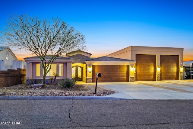 view of front of home featuring stone siding, stucco siding, concrete driveway, and a garage