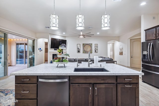 kitchen with arched walkways, dark brown cabinetry, black fridge with ice dispenser, dishwasher, and open floor plan