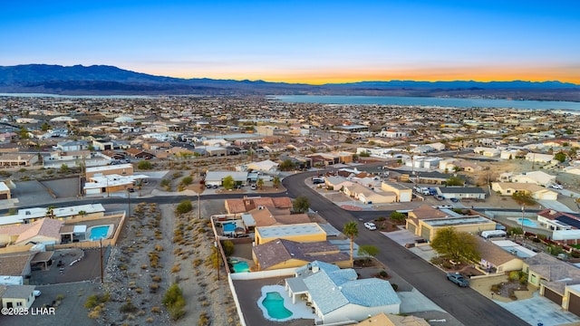 aerial view at dusk featuring a mountain view and a residential view