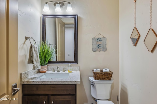 half bathroom featuring vanity and toilet