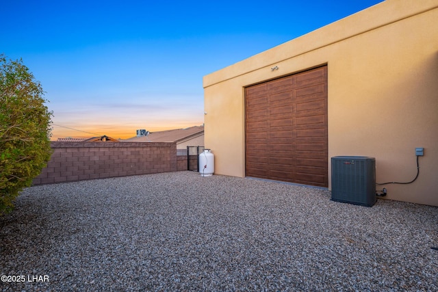 yard at dusk with central AC and fence