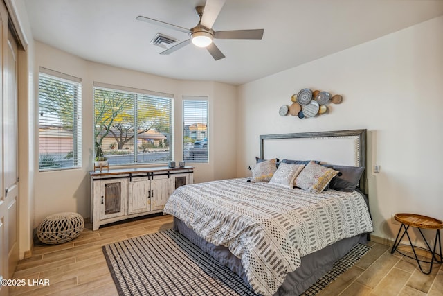 bedroom featuring multiple windows, baseboards, visible vents, and wood tiled floor