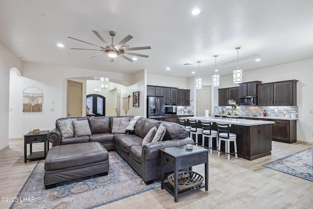 living area with arched walkways, recessed lighting, light wood finished floors, and baseboards