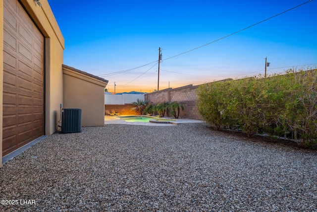 view of yard featuring a garage, central AC unit, a fenced backyard, and a patio area