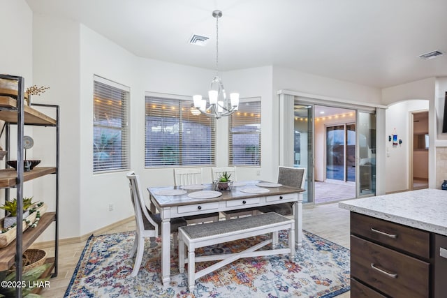 dining space featuring a notable chandelier, light wood-style flooring, baseboards, and visible vents