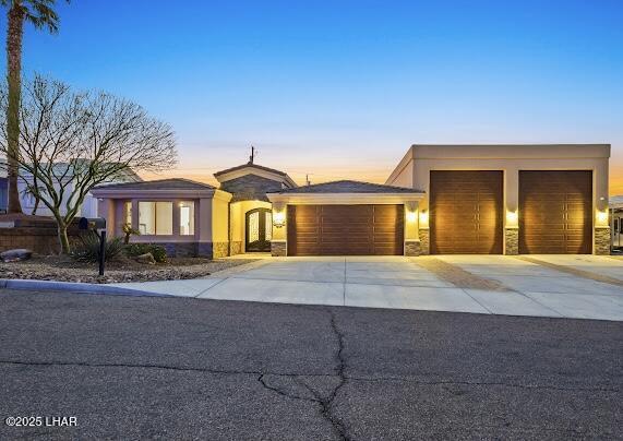 view of front of home with stucco siding, stone siding, concrete driveway, and an attached garage