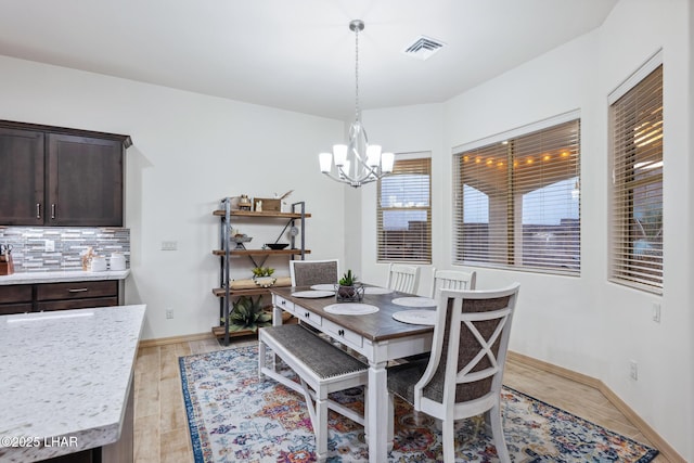 dining area with visible vents, baseboards, a notable chandelier, and light wood finished floors