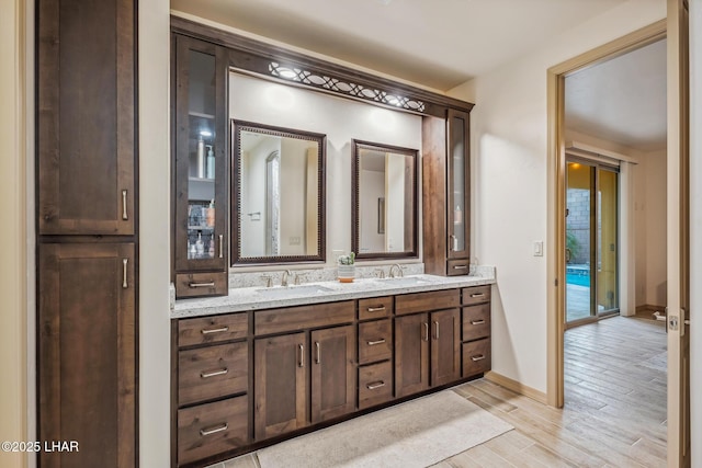 bathroom featuring double vanity, a sink, baseboards, and wood finished floors