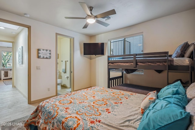 bedroom with visible vents, connected bathroom, baseboards, a skylight, and wood finished floors