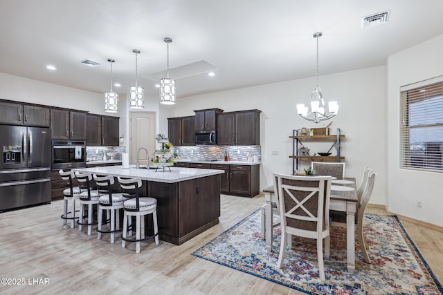 kitchen with visible vents, dark brown cabinets, appliances with stainless steel finishes, and decorative backsplash