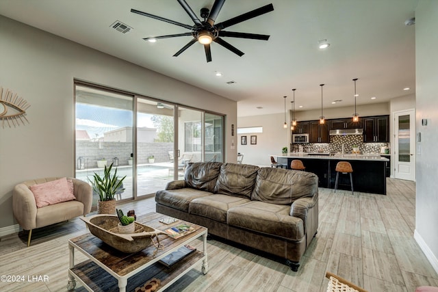 living room featuring light wood-style floors, baseboards, a ceiling fan, and visible vents