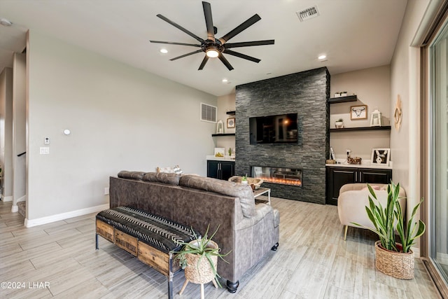 living room featuring visible vents, baseboards, a ceiling fan, and a fireplace