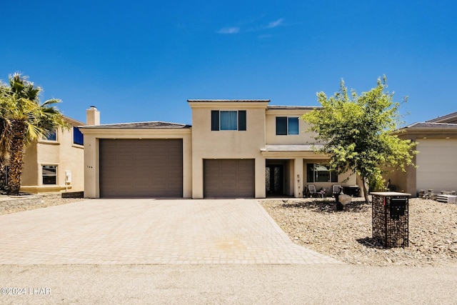 view of front of property featuring a chimney, driveway, stucco siding, and a garage