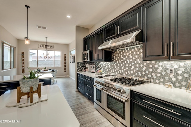 kitchen with an inviting chandelier, light countertops, under cabinet range hood, visible vents, and stainless steel appliances
