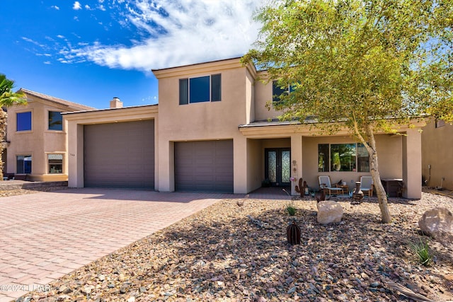 view of front of house with a garage, stucco siding, decorative driveway, and french doors