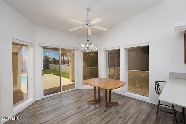 dining space featuring wood finished floors, baseboards, and ceiling fan with notable chandelier