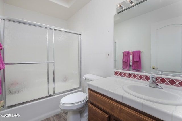 full bathroom with toilet, backsplash, wood finished floors, vanity, and enclosed tub / shower combo