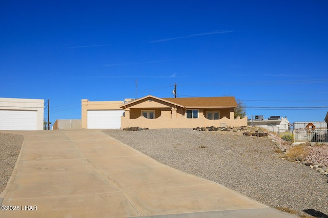 ranch-style home featuring a garage, driveway, fence, and stucco siding