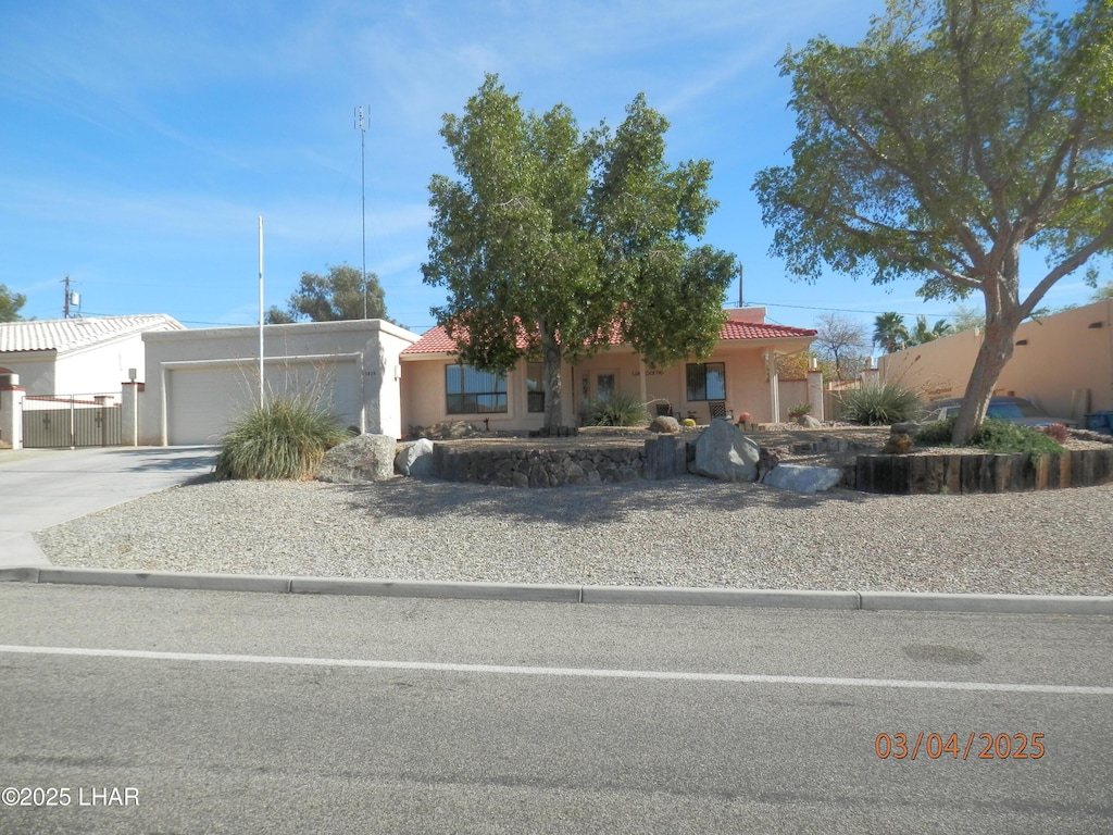 view of front of house featuring a garage, concrete driveway, stucco siding, and a tiled roof