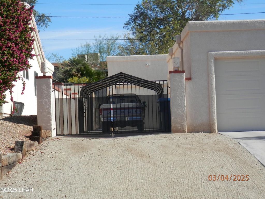 garage featuring concrete driveway and a gate