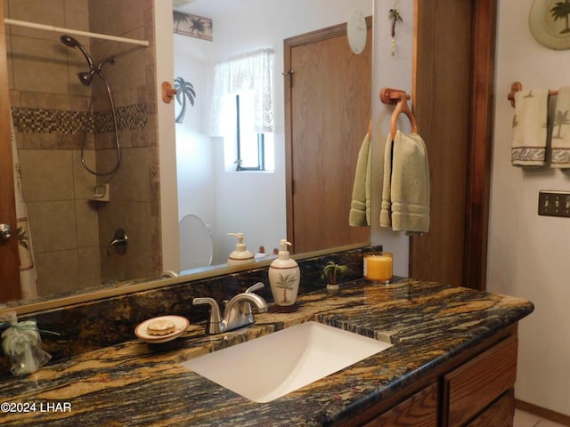 bathroom featuring tiled shower and vanity