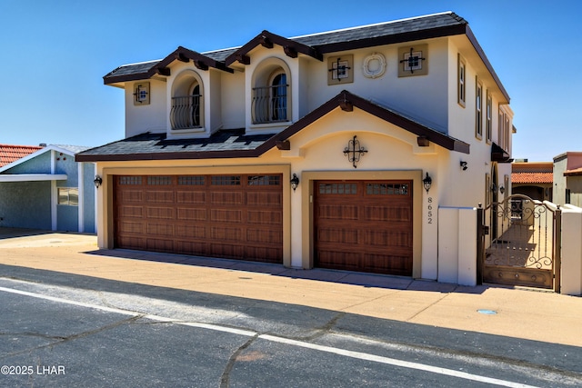 8652 Hopi Dr, Parker, AZ 85344 - mediterranean / spanish-style home with an attached garage, stucco siding, and a gate