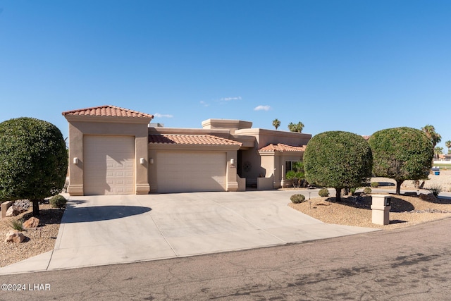 view of front facade with driveway, an attached garage, a tile roof, and stucco siding