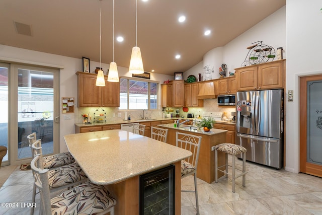 kitchen with wine cooler, a breakfast bar, a sink, appliances with stainless steel finishes, and an island with sink