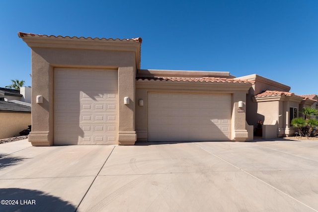 view of front facade with driveway, a tiled roof, an attached garage, and stucco siding