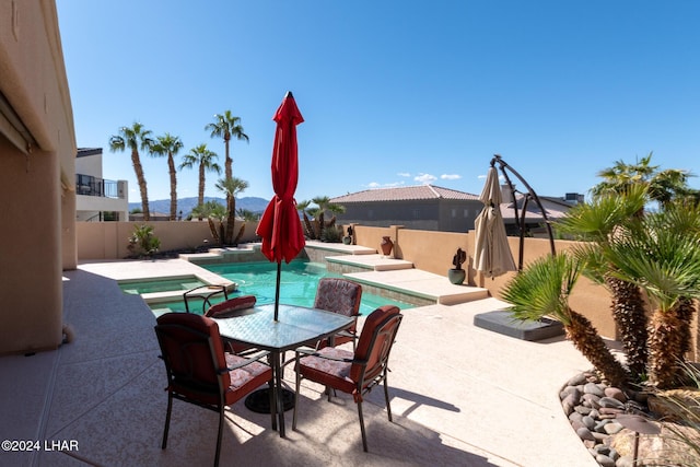 view of pool with outdoor dining space, a fenced backyard, a pool with connected hot tub, and a patio