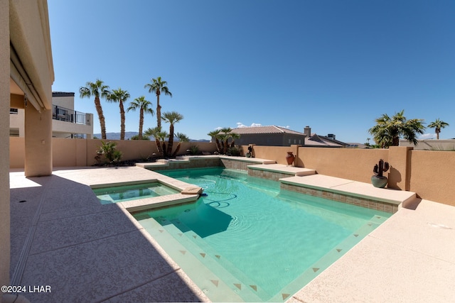 view of swimming pool with a patio area, a pool with connected hot tub, and a fenced backyard