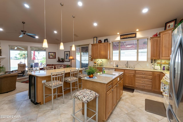 kitchen with a breakfast bar, a sink, backsplash, freestanding refrigerator, and a center island with sink