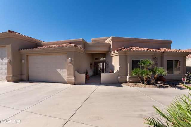 view of front facade featuring a garage, concrete driveway, a tiled roof, and stucco siding