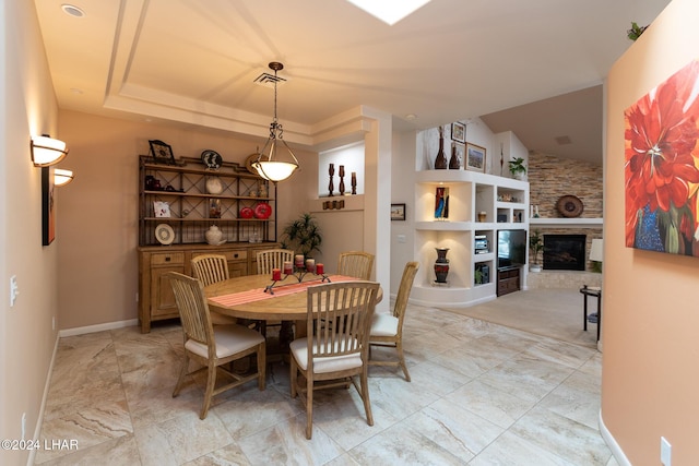 dining room with lofted ceiling, built in shelves, a fireplace, visible vents, and baseboards